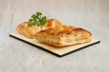 Two Puff with ham and cheese on a wooden cutting board laying on a grey background, side view,...