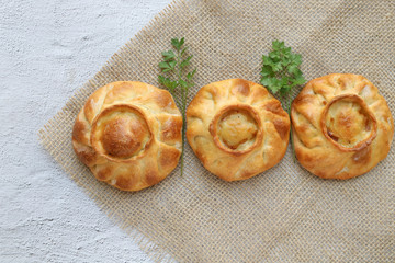 Three traditional russian chicken pies called kurnik on a table napkin laying on a grey background, top view, horizontal © Lyudmila