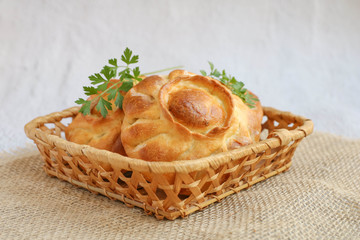 Traditional russian chicken pies kurnik in a wicker basket laying on a table napkin on a grey background, side view, horizontal © Lyudmila