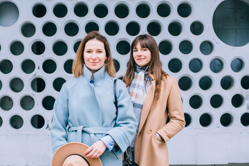 Portrait of two stylish adult serious emotion women siters walking in the city outdoor. Family,...
