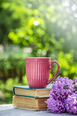 Mug on stack of books. Pink cup. Cup of coffee and books. Cup of tea.