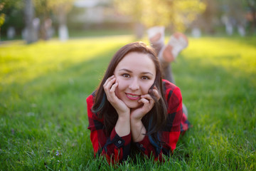 teen girl lying on the grass on a Sunny day and smiling, girl with developed body smiling in the Park on the lawn
