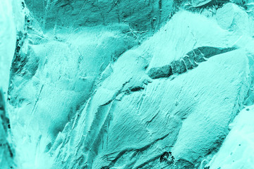 Vintage azure background. Rough painted wall of turquoise color. Imperfect plane of cyan colored. Uneven old decorative toned backdrop of aqzure tint. Texture of teal hue. Ornamental stony surface.