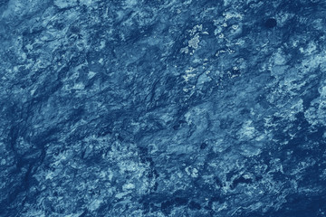 Vintage blue background. Rough painted wall of sapphire color. Imperfect plane of blue colored. Uneven old decorative toned backdrop of cyan tint. Texture of sapphirine hue. Ornamental stony surface.