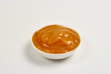 Orange sauce in white plate on white background.