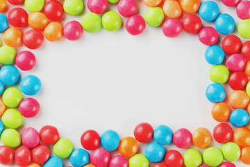 Frame of multi-colored candies close up. Rainbow colored dragee multicolored glaze on a white background