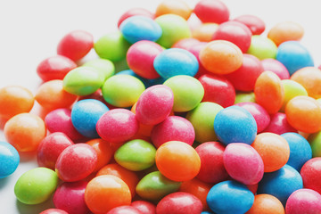 A rainbow of color from multicolored candies close-up, multi-colored glaze dragee on a white background