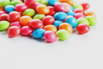 A rainbow of color from multicolored candies close-up, multi-colored glaze dragee on a white background
