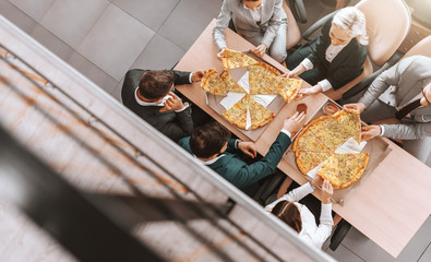 Top view of business people in formal wear eating pizza together at place of work. Success at work starts by adopting a positive attitude.