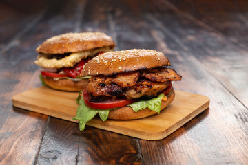 Two homemade beef burgers with fried potato on wooden cutting board