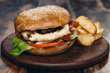 Classic american hamburger with french fries on a wooden board