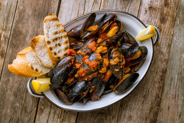 Mussels in tomato sauce on wooden background