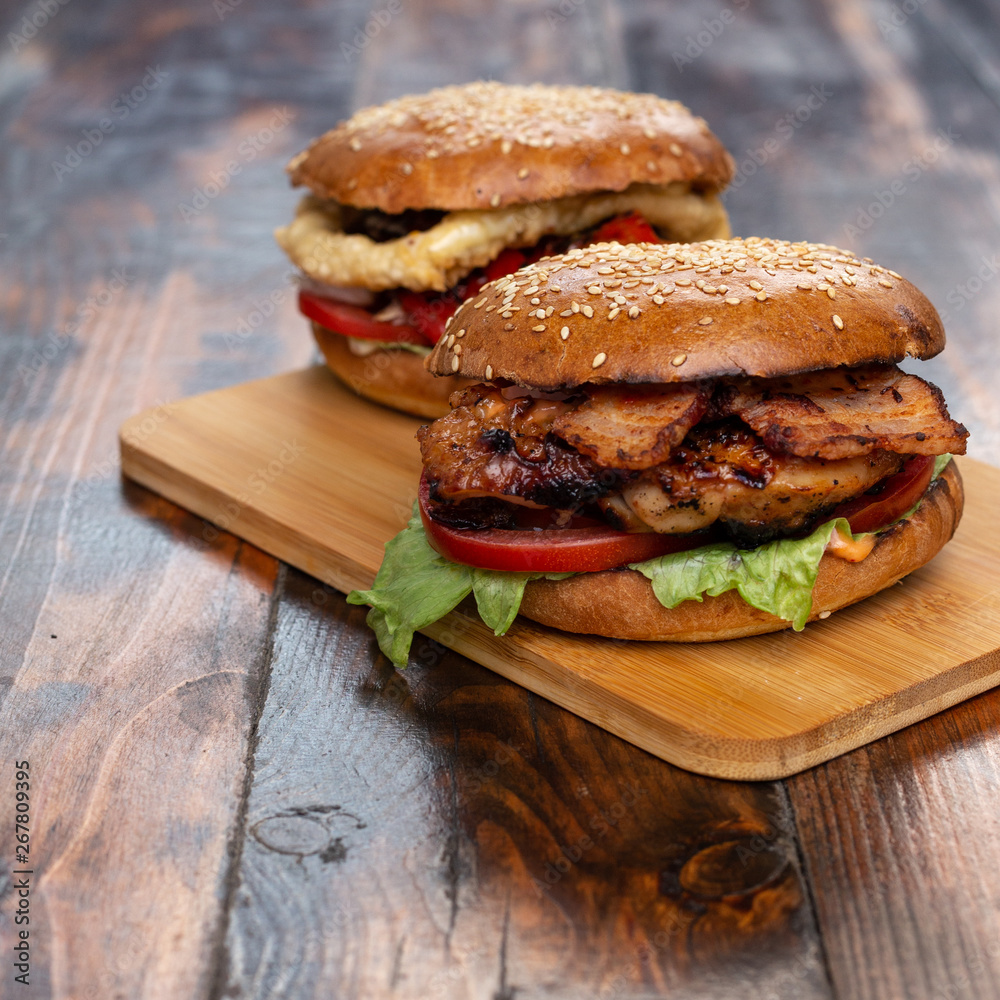 Wall mural Two homemade beef burgers with fried potato on wooden cutting board