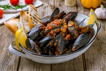Mussels in tomato sauce on wooden background