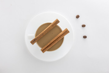 White cup of hot coffee and Cinnamon sticks .