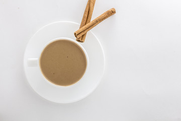 White cup of hot coffee and Cinnamon sticks .