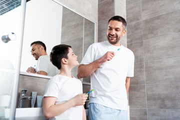 Fototapeta premium happy father and son brushing teeth in bathroom
