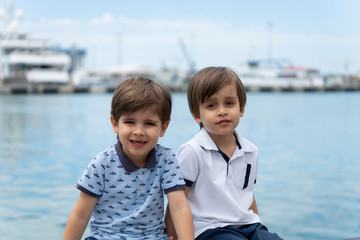 Two twin brothers of the model are sitting next to each other in fashionable clothes on the...
