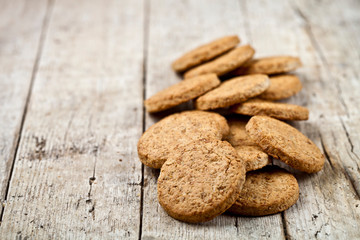 Fresh baked oat cookies heap on rustic wooden table background.