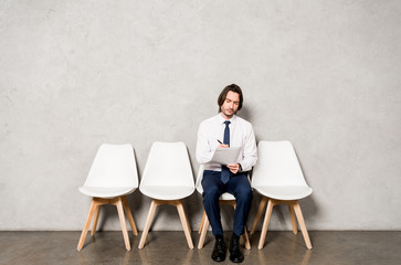 Fototapeta premium handsome man sitting on chair while waiting job interview in office
