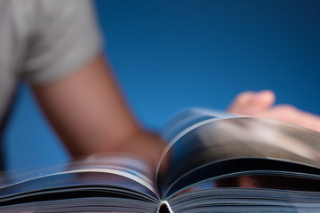 A man is flipping through a book. Focus on book binding.