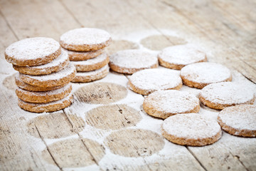 Fresh baked oat cookies with sugar powder on rustic wooden table background.