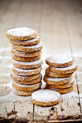 Fresh oat cookies stacks with sugar powder closeup on rustic wooden table.