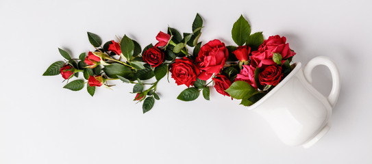 Creative layout made of coffee or tea cup with red roses on white background