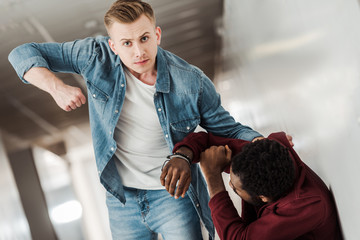 two students in jeans fighting in corridor in college