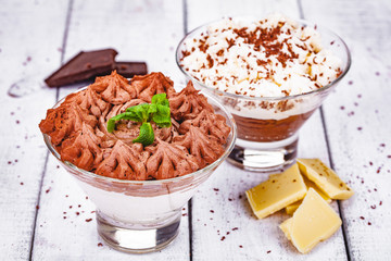 Homemade chocolate mousse in portion glasses on wooden background. Close up