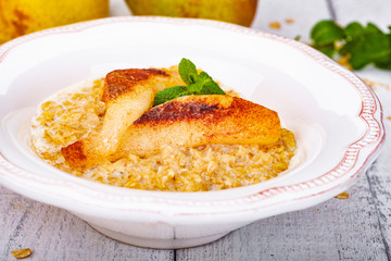 Oatmeal porridge with pear in white plate. Close up