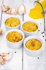 Polenta with mushrooms in white ramekin bowls on wooden rustic table. Close up
