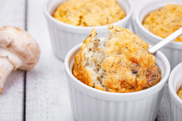 Polenta with mushrooms in white ramekin bowls on wooden rustic table. Close up