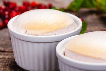 Souffle with cranberries in white ramekin on wooden rustic table. Close up
