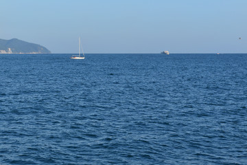 Fototapeta premium A small yacht in the waters of the Black Sea, in the distance, against the blue sky