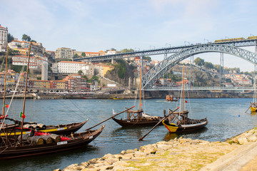 Port wine boats on Douro River with Dom Luis I Bridge and the old town background, at Ribeira, Porto, Portugal
