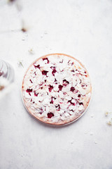 Whole cherry cake with almond petals and sugar powder on white background with cherry flowers.