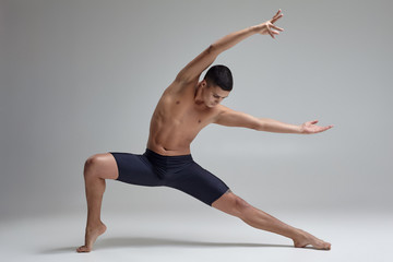Photo of a handsome man ballet dancer, dressed in a black shorts, making a dance element against a...