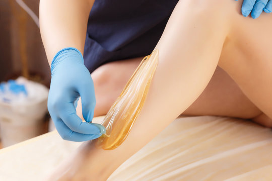 Close-up Of A Beautician shugaring depilation Woman's Leg In Beauty Spa. Body hair removal