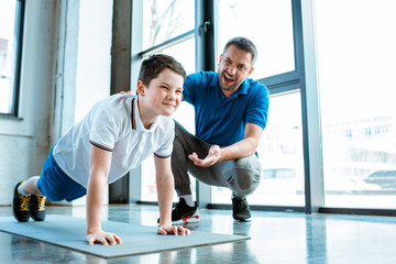 father helping son with push up exercise at gym