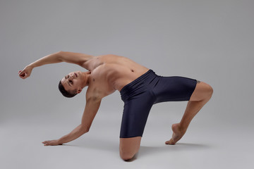 Photo of a handsome man ballet dancer, dressed in a black shorts, making a dance element against a...