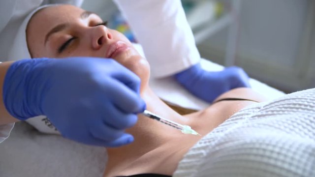 Beautician makes injections, anti-aging procedures for tightening and smoothing wrinkles on the skin of the breast and neck of a woman.