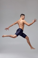 Photo of a handsome man ballet dancer, dressed in a black shorts, making a dance element against a...
