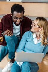 Smiling multicultural students in glasses using laptop in lecture hall