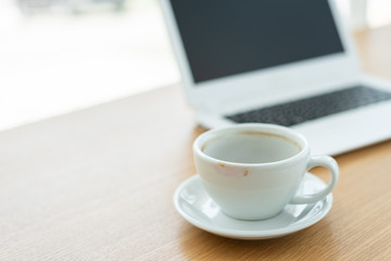 empty cup of coffee with laptop on the table