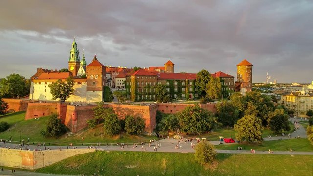 Historic royal Wawel Cathedral with Sigismund Chapel and castle in Cracow, Poland, in red sunset light with a rainbow and Vistula river, park and promenade. Aerial 4K approaching video  in spring