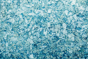 Fototapeta na wymiar Broken glass fragments on a blue background. Background of broken glass fragments. View from above.