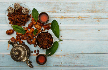 Fototapeta na wymiar Traditional Arabic, Turkish Ramadan tea with dry dates and raisins on a wooden white table. A cup of tea on a white table.Turkish fresh tea with dates. Ramadan kareem. Ramadan background. 
