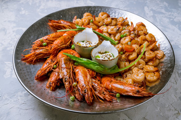 some langoustines on a plate on grey concrete and grilled shrimps