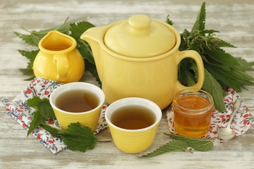 Nettle tea in cups and tea pot, fresh nettle